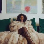 Ms Banks wearing a fur coat sat on a green sofa
